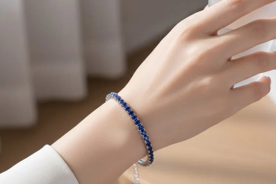 Hand wearing a blue tennis bracelet with a blurred background