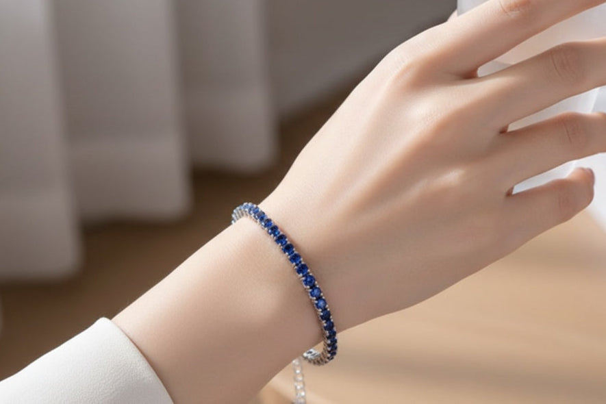Hand wearing a blue tennis bracelet with a blurred background